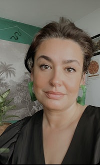 a woman wearing a black top and green earrings